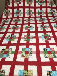 a red and white quilt on top of a bed