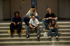 four young people sitting on steps with skateboards