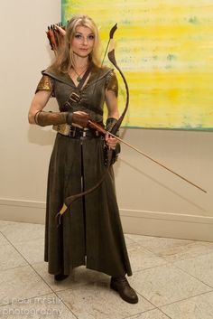 a woman dressed up as the lord of the rings holding a bow and arrow in her hand