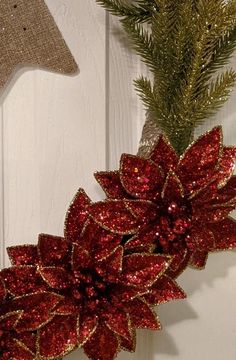 a red poinsettia hanging on the side of a white wooden wall next to a star