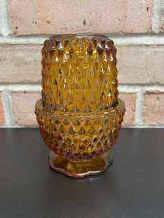 a yellow glass candle holder sitting on top of a table