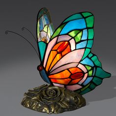 a stained glass butterfly sitting on top of a bronze base with an intricate design around it's wings