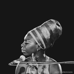 a woman with a microphone in front of a black and white photo on a stage