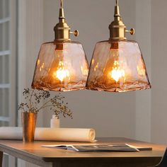 two clear glass pendant lights hanging over a wooden table