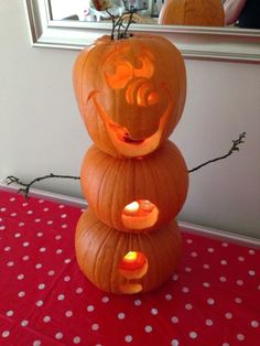 three pumpkins stacked on top of each other with faces carved into them and lit candles in the middle