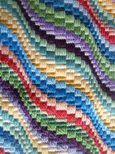 a multicolored crocheted blanket is laying on the floor