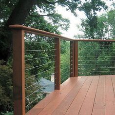 a wooden deck with metal railing and trees in the background