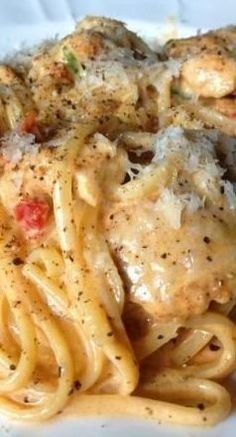 a white plate topped with pasta and meat covered in grated parmesan cheese