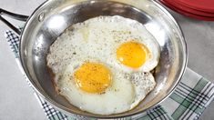 two fried eggs in a pan on a table