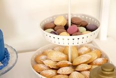 two tiered trays filled with different types of cookies and pastries next to a blue cake