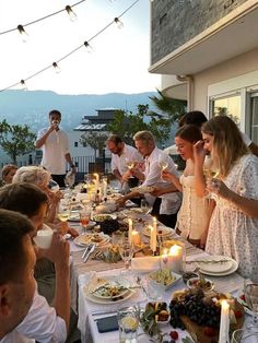 a group of people standing around a table with food and drinks in front of them