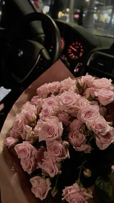 a bouquet of pink roses sitting on top of a table in front of a car