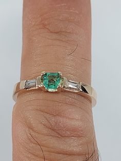 This stunning Emerald and Diamond Ring has been carefully crafted in warm 10K Yellow Gold , Authentic Emerald and Diamonds. Great for any occasion! Buy it for your-self or buy it for someone you love! Ring Weight and Stones Measurements: Ring weights 2.5 grams. Material: 10K Yellow Gold, Emerald and Diamonds Emerald Measurements:  3.5 mm  (Color:Green) Diamonds: 2 Diamond Baguette: 3.0 mm x 1.5 mm each , 0.06 ct Total Weight: 0.12 ct Ring Size: 7 1/2  All of my jewelry is handmade from scratch and of high quality. Ring can be resized at no extra cost and it will shipped to you in an elegant gift box. thanks for visiting my shop! have a blessed day! I gladly accept returns and exchanges Just contact me within: 3 days of delivery Ship items back to me within: 7 days of delivery, items should Green Three Stone Baguette Cut Ring, Green Baguette Cut Three Stone Rings, Emerald Ring With Center Stone In Baguette Cut, Emerald Ring With Baguette Cut Center Stone, Emerald Rings With Baguette Cut And Accent Stones, Emerald Baguette Cut Ring With Accent Stones, Emerald Baguette Cut Ring With Center Stone, 14k Gold Three-stone Baguette Cut Ring, 14k Gold Three Stone Baguette Cut Ring