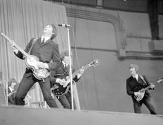 the rolling stones performing on stage in front of microphones and guitar players, with one man