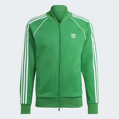 A TRACK JACKET MADE IN PART WITH A BLEND OF RECYCLED AND RENEWABLE MATERIALS. Adidas Three Stripes Outerwear For Sports Events, Adidas Outerwear With Three Stripes For Sports Events, Three Stripes Track Jacket For Sports Events, Adidas Green Winter Track Jacket, Green Adidas Winter Track Jacket, Winter Adidas Green Track Jacket, Green Sportswear Track Jacket For Fall, Sporty Green Track Jacket With Ribbed Cuffs, Green Sporty Track Jacket With Ribbed Cuffs