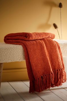 an orange blanket sitting on top of a white bench