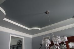 a chandelier hanging from the ceiling in a room with gray walls and white trim