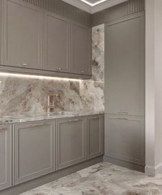 a large kitchen with marble counter tops and gray cabinetry, along with gold accents