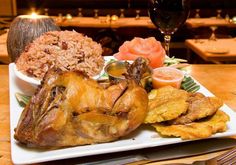 a white plate topped with meat and rice next to a glass of wine