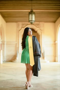 a woman in a green dress is holding a black jacket and yellow tie while standing on the floor