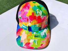 a colorful hat sitting on top of a white table covered in green and yellow paint