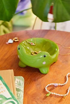 a green elephant shaped bowl sitting on top of a wooden table next to a book