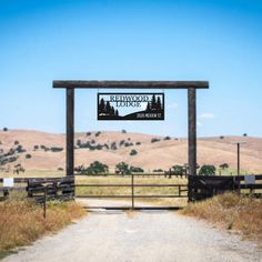 a sign that is on the side of a dirt road in front of a fence