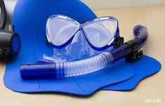 a blue hard hat, goggles and snorkels on a wooden table