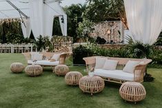 wicker couches and chairs on the grass in front of an outdoor wedding venue