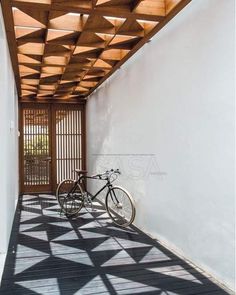 a bicycle is parked on the floor in front of a white wall and wooden slatted ceiling