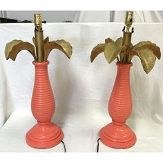 two orange vases with gold leaves on them sitting side by side against a white backdrop