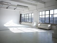 an empty room with large windows and white furniture