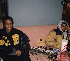 two young men sitting on a couch next to each other with headphones in their ears