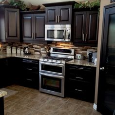 a kitchen with black cabinets and stainless steel appliances