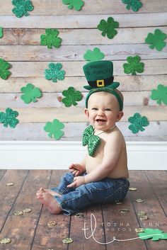 a baby is sitting on the floor wearing a green hat and shamrocks for st patrick's day