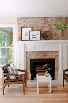 a living room with two chairs and a fire place in front of a brick fireplace