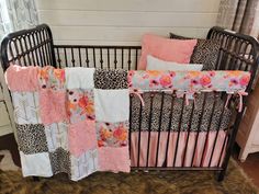 a baby crib with pink, black and white bedding