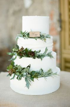 a white wedding cake with greenery on top