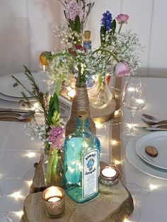 a table topped with candles and vases filled with flowers on top of a wooden slice