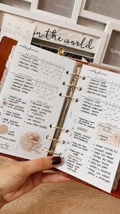 a hand holding a planner with the words in the world written on it