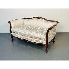 an antique style couch with white upholstered fabric