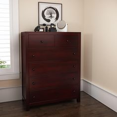 a brown dresser sitting next to a window in a room with white walls and wooden floors