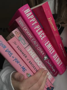 a person holding a stack of pink books