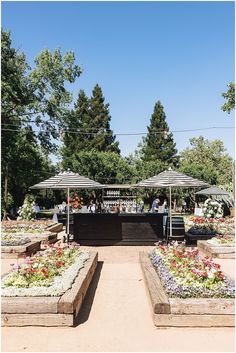 an open air market with lots of flowers and plants in the foreground, on a sunny day