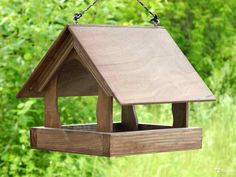 a wooden bird feeder hanging from a tree