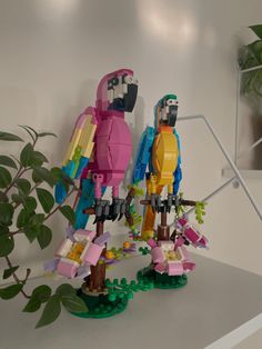 two lego figurines standing next to each other on a shelf near a potted plant