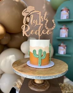 a cake sitting on top of a wooden table next to balloons and a sign that says, myst rodeo