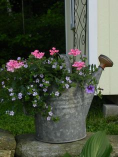 a metal watering can filled with pink and purple flowers