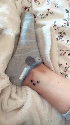 a person with a small tattoo on their arm laying in bed next to a blanket