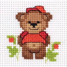 a cross stitch teddy bear with a red hat and vest on it's chest